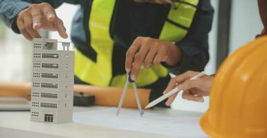 reunión de trabajo en equipo de ingenieros, trabajo de dibujo en la reunión de planos para el trabajo del proyecto con un socio en la construcción de modelos y herramientas de ingeniería en el concepto de sitio de trabajo, construcción y estructura. foto