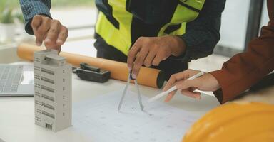 reunión de trabajo en equipo de ingenieros, trabajo de dibujo en la reunión de planos para el trabajo del proyecto con un socio en la construcción de modelos y herramientas de ingeniería en el concepto de sitio de trabajo, construcción y estructura. foto