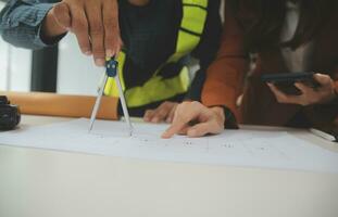 reunión de trabajo en equipo de ingenieros, trabajo de dibujo en la reunión de planos para el trabajo del proyecto con un socio en la construcción de modelos y herramientas de ingeniería en el concepto de sitio de trabajo, construcción y estructura. foto