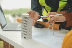 reunión de trabajo en equipo de ingenieros, trabajo de dibujo en la reunión de planos para el trabajo del proyecto con un socio en la construcción de modelos y herramientas de ingeniería en el concepto de sitio de trabajo, construcción y estructura. foto