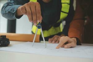 reunión de trabajo en equipo de ingenieros, trabajo de dibujo en la reunión de planos para el trabajo del proyecto con un socio en la construcción de modelos y herramientas de ingeniería en el concepto de sitio de trabajo, construcción y estructura. foto