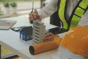 reunión de trabajo en equipo de ingenieros, trabajo de dibujo en la reunión de planos para el trabajo del proyecto con un socio en la construcción de modelos y herramientas de ingeniería en el concepto de sitio de trabajo, construcción y estructura. foto