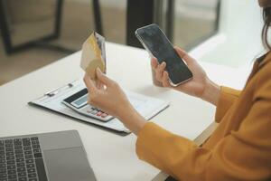 mujer participación crédito tarjeta y utilizando teléfonos inteligentes a casa.online compras, Internet bancario, Tienda en línea, pago, gasto dinero, comercio electrónico pago a el almacenar, crédito tarjeta, concepto foto