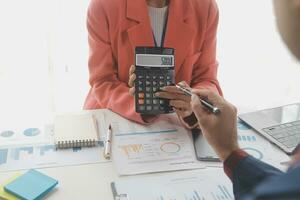 Close up Business woman using calculator and laptop for do math finance on wooden desk, tax, accounting, statistics and analytical research concept photo