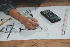 Team of multiethnic architects working on construction plans in meeting room. Engineers discussing on project in office. Mature businessman and woman standing around table working on blueprint. photo