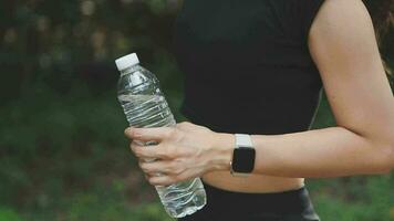 Bebiendo agua, aptitud y ejercicio mujer después Deportes correr y formación en naturaleza. ejercicio, excursionismo y caminando desafío con un botella de un hembra corredor en verano Listo para corriendo para salud video