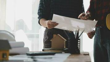 Image of team engineer checks construction blueprints on new project with engineering tools at desk in office. video