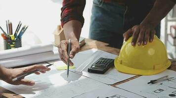 beeld van team ingenieur cheques bouw blauwdrukken Aan nieuw project met bouwkunde gereedschap Bij bureau in kantoor. video