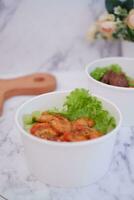 Shrimp salad in white bowl table background, top view photo