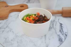 Rice with beef and vegetables in a white bowl table photo