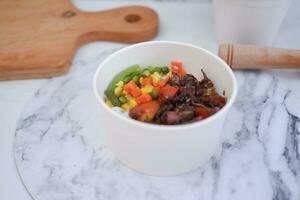 Rice with beef and vegetables in a white bowl table photo