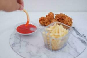 French fries, fried chicken and ketchup on white marble table. photo