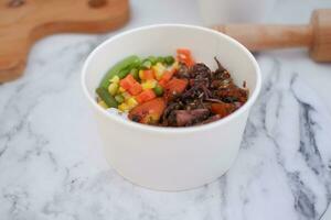 Rice with beef and vegetables in a white bowl table photo