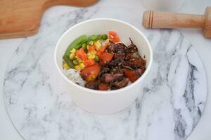 Rice with beef and vegetables in a white bowl table photo