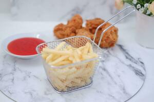 French fries, fried chicken and ketchup on white marble table. photo