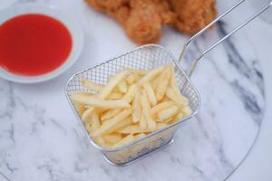 French fries, fried chicken and ketchup on white marble table. photo