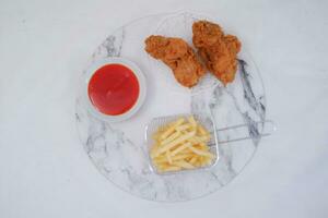 French fries, fried chicken and ketchup on white marble table. photo