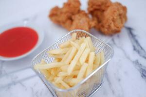 French fries, fried chicken and ketchup on white marble table. photo