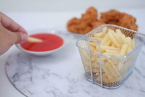 French fries, fried chicken and ketchup on white marble table. photo