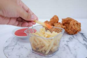 French fries, fried chicken and ketchup on white marble table. photo