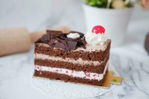 Chocolate cake with whipped cream and cherries on white marble background photo