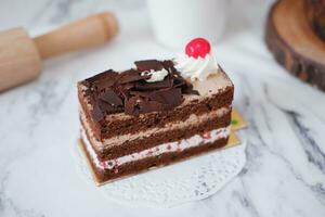 Chocolate cake with whipped cream and cherries on white marble background photo