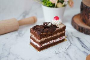 Chocolate cake with whipped cream and cherries on white marble background photo