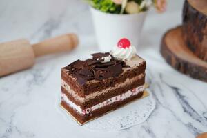 Chocolate cake with whipped cream and cherries on white marble background photo
