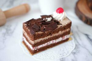 Chocolate cake with whipped cream and cherries on white marble background photo