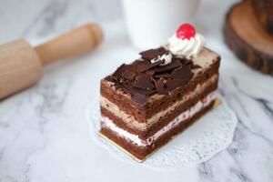Chocolate cake with whipped cream and cherries on white marble background photo