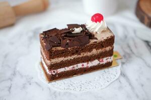 Chocolate cake with whipped cream and cherries on white marble background photo