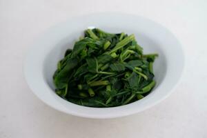 Stir-fried spinach in a white bowl on a white background photo