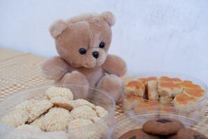 Teddy bear and cookies in plastic box on wooden table background. photo