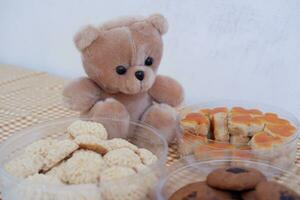 Teddy bear and cookies in plastic box on wooden table background. photo