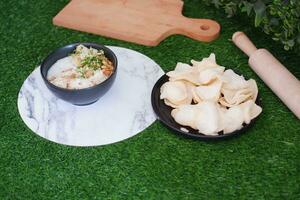 Rice porridge with chicken in white plate on green grass background photo