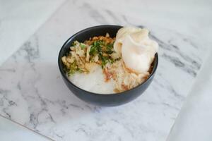 arroz gachas de avena con pollo en negro cuenco en blanco mármol mesa foto