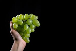 Hand holding green grapes bunch isolated on black background with copy space. ai generated photo