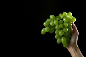 Hand holding green grapes bunch isolated on black background with copy space. ai generated photo