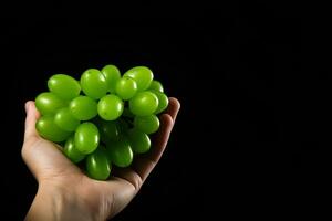 Hand holding green grapes bunch isolated on black background with copy space. ai generated photo