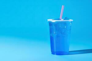 Blue drink in a plastic cup isolated on a blue background. Take away drinks concept with copy space. ai generated photo