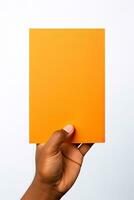 A human hand holding a blank sheet of orange paper or card isolated on a white background. ai generated photo