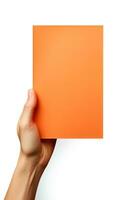 A human hand holding a blank sheet of orange paper or card isolated on a white background. ai generated photo