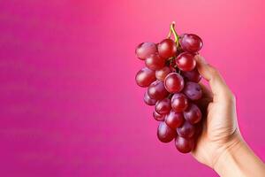 Hand holding a bunch of red grapes isolated on a red background with copy space. ai generated photo