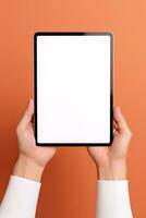 Hand holding tablet with mockup blank screen isolated on orange background. ai generated photo