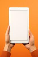 Hand holding tablet with mockup blank screen isolated on orange background. ai generated photo