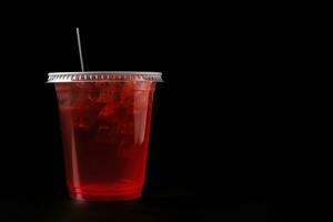 Red drink in a plastic cup isolated on a black background. Take away drinks concept with copy space. ai generated photo