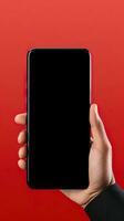 Hand holding smartphone with a black blank screen isolated on a red background. ai generated photo