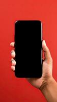 Hand holding smartphone with a black blank screen isolated on a red background. ai generated photo