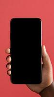 Hand holding smartphone with a black blank screen isolated on a red background. ai generated photo