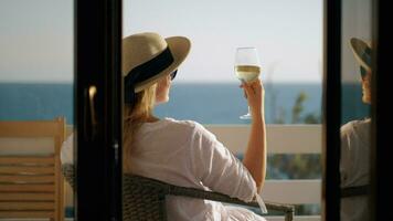 donna rilassante nel solitudine lei potabile vino e godendo mare Visualizza video